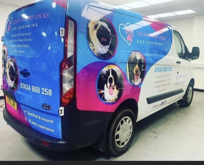 The Lola's Luxury Locks mobile grooming van, wrapped in blue and pink livery, parked indoors